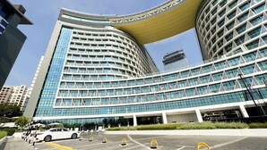 A modern hotel with a curved facade, multiple floors, and a distinctive yellow overhang. - Elegant Palm Studio with Sea View & Pool (Dubai)