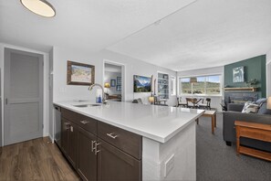 Eine moderne Küche mit einer großen Kochinsel, Holzschränken und einem Essbereich mit einer Couch und einem Tisch.