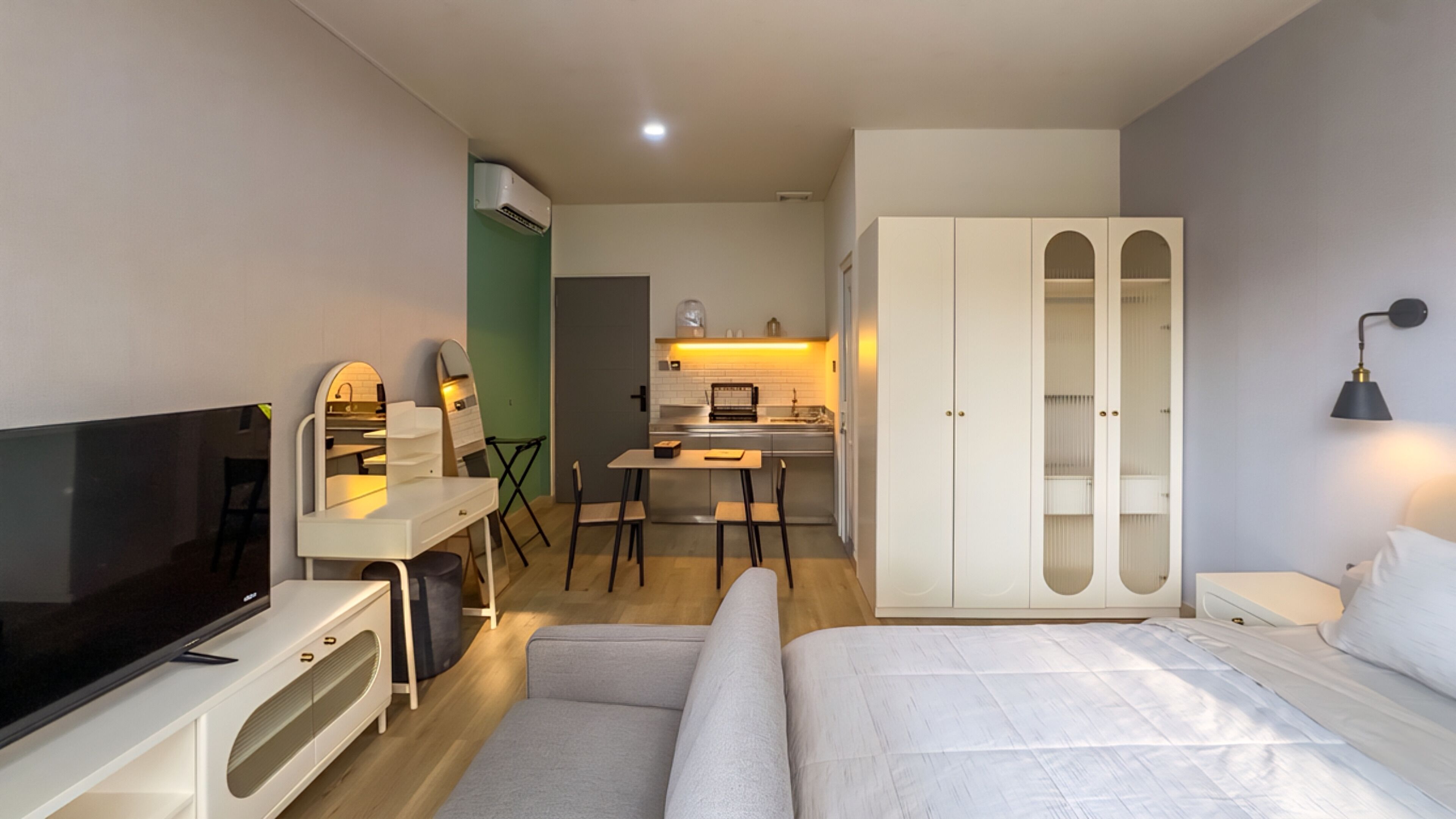 Ein kleines Hotelzimmer mit Fernseher, einer Sitzecke, einem Essbereich und einem Kleiderschrank.