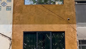 Un edificio de dos pisos con techo plano, ventanas grandes y un letrero que dice Roemah Roti.