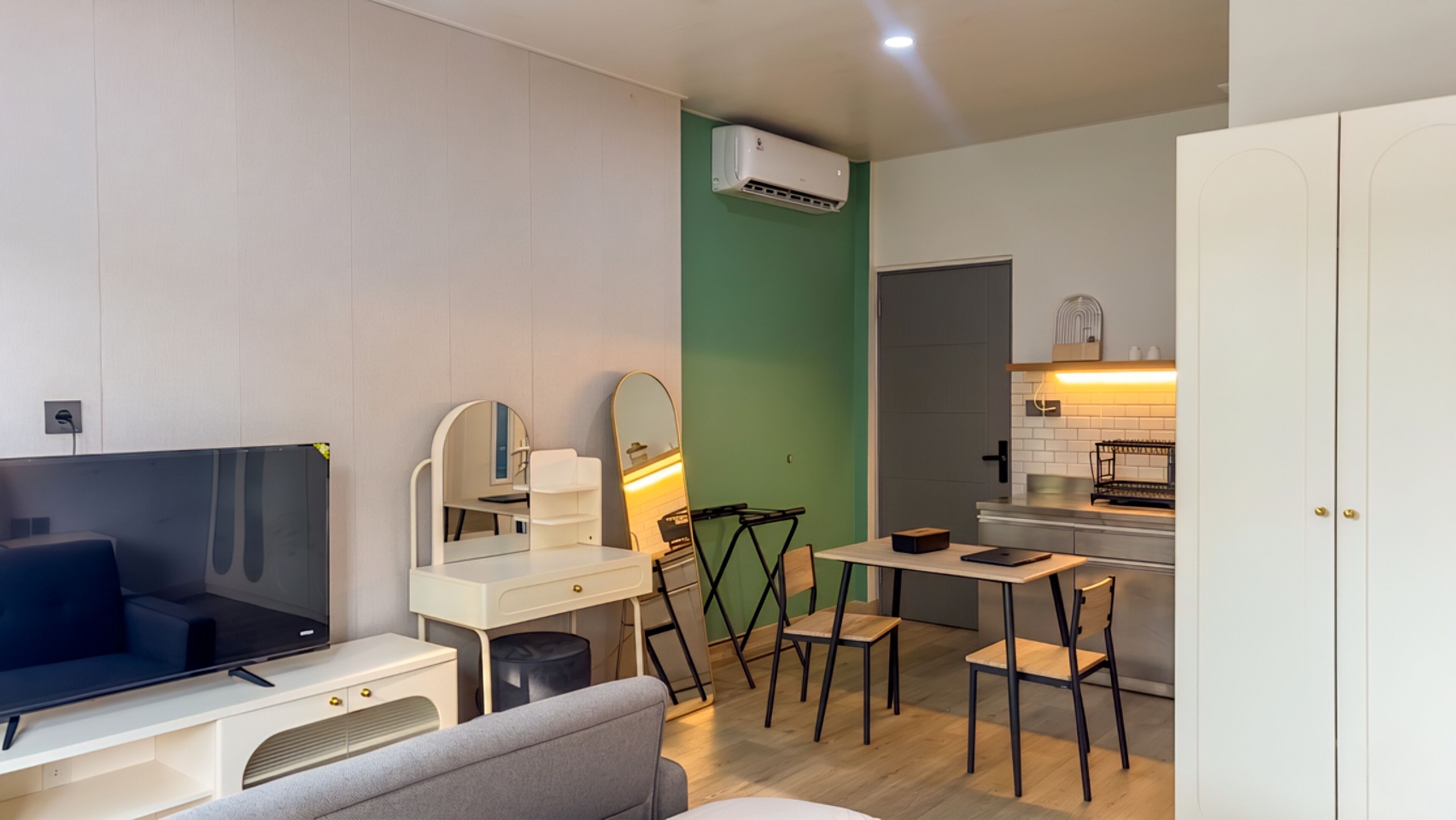 A modern living room with a TV, seating, a dining area, and a kitchen.