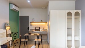 Una cocina compacta con comedor, un armario blanco de puertas de vidrio y una pared decorada en verde.