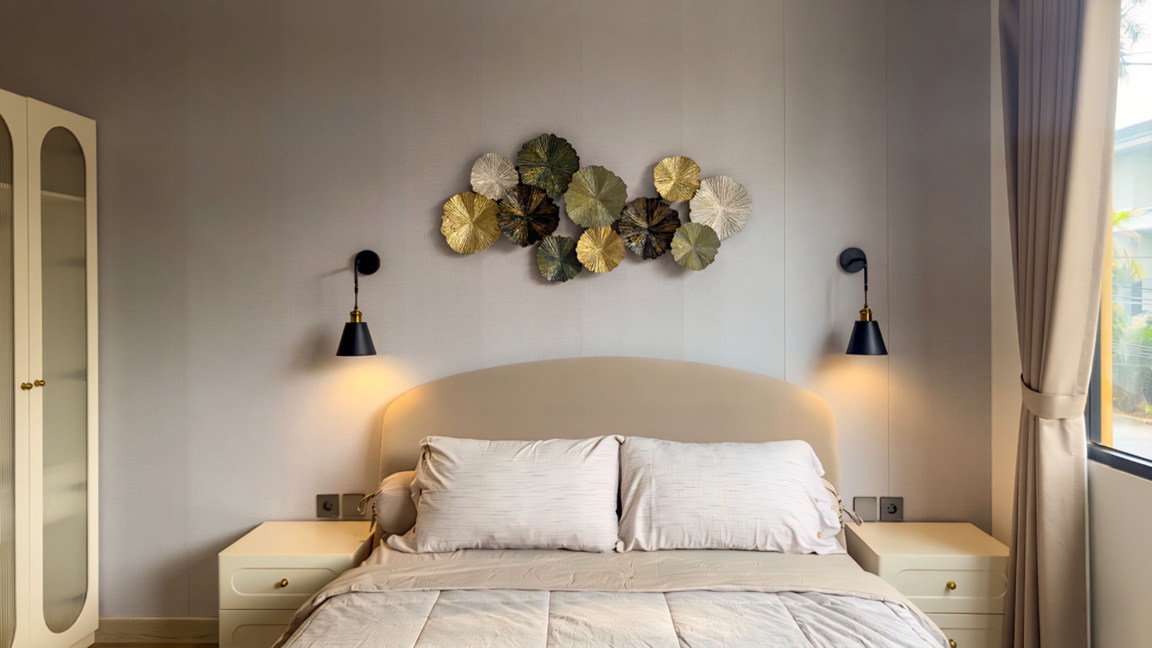 A bedroom with a bed, bedside tables, wall-mounted lamps, and a decorative wall piece.