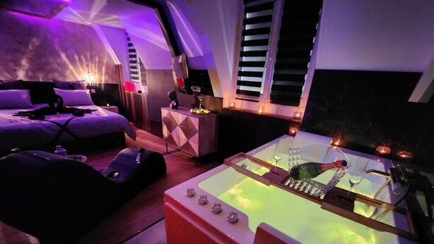 Ein Zimmer mit einem Bett, einem Massagesessel, einer Massageliege und einer Whirlwanne.
