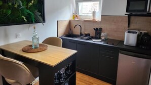 Eine kompakte Küche mit Essbereich, einem schwarzen Kühlschrank, einer Mikrowelle und einem Fenster mit Tageslicht.