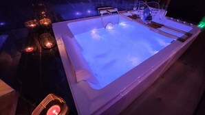 Eine Sitzecke mit Whirlpool, Marmorwand und Kerzen.