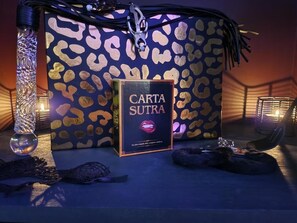 Un livre intitulé « Carta Sutra » est posé sur une table, à côté d’un sac à motifs léopard et de quelques objets décoratifs.