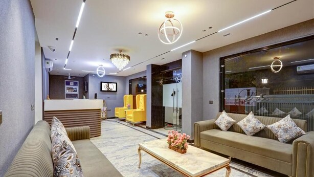 A modern hotel lobby with a reception desk, seating area, and a large window. - Limewood Stay Premium Studios Sector 29 (Gurugram)
