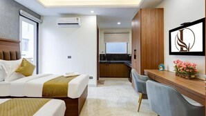 A hotel room with a bed, a desk, a chair, a kitchenette, and a TV. - Limewood Stay Premium Studios Sector 29 (Gurugram)