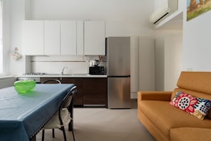 A modern kitchen with white cabinets, a stainless steel refrigerator, and a dining table with a green bowl. - Cozy 45m2 apartment, ideal for 4 people, located on the first floor of a building without a lift (steps to access).The accommodation is located in a strategic area, a stone's throw from the M3/M5 Zara stop and the stops of numerous surface transport ve (Milan)
