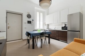 A compact kitchen with white cabinets, a stainless steel refrigerator, and a dining area with a table and chairs. - Cozy 45m2 apartment, ideal for 4 people, located on the first floor of a building without a lift (steps to access).The accommodation is located in a strategic area, a stone's throw from the M3/M5 Zara stop and the stops of numerous surface transport ve (Milan)