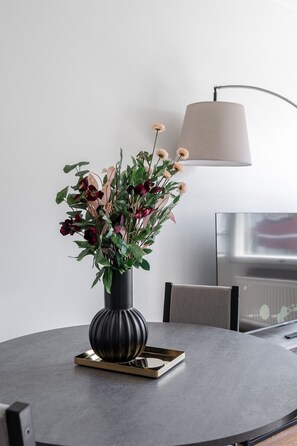 Et rundt bord med en blomstervase, en lampe og en bakke.