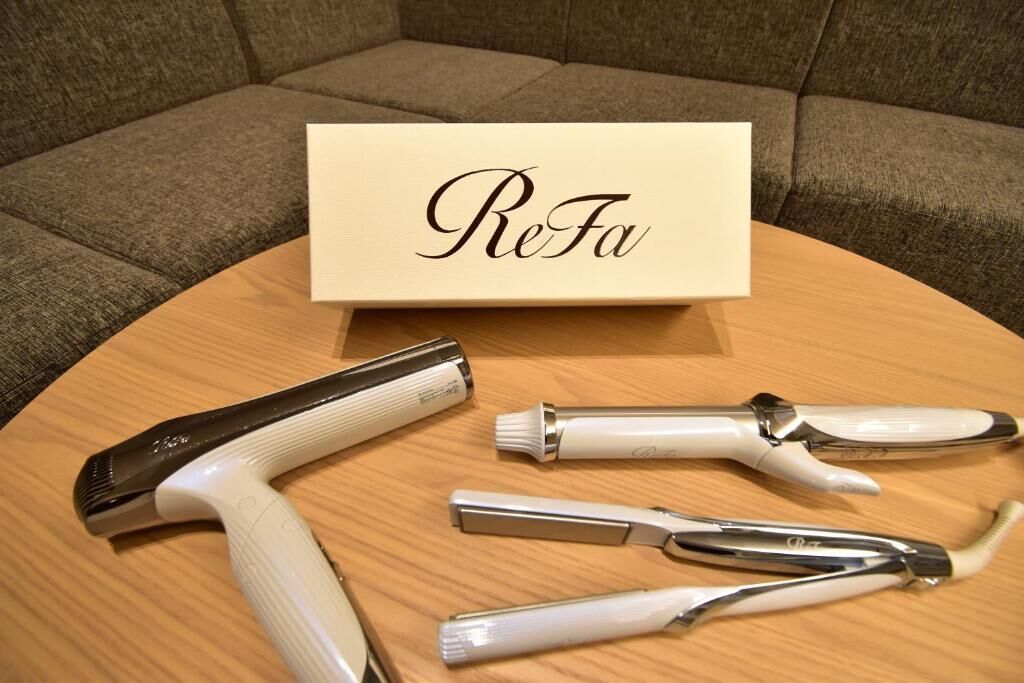 A wooden table with a ReFa sign and three curling irons.