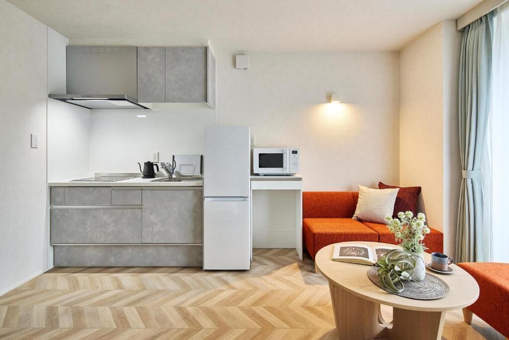 A compact living space with a kitchenette, a sofa, a coffee table, and a window with curtains.