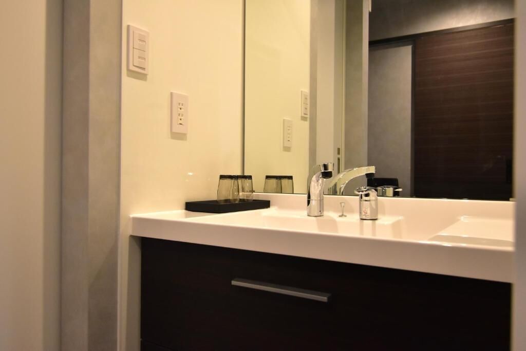 A bathroom with a white sink, a mirror, and a dark cabinet below.
