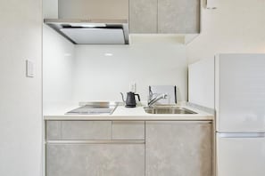 A modern kitchen with a stainless steel range hood, a double sink, and a built-in refrigerator.
