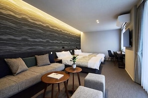A modern hotel room with a large bed, a sofa, a small table, and a TV.
