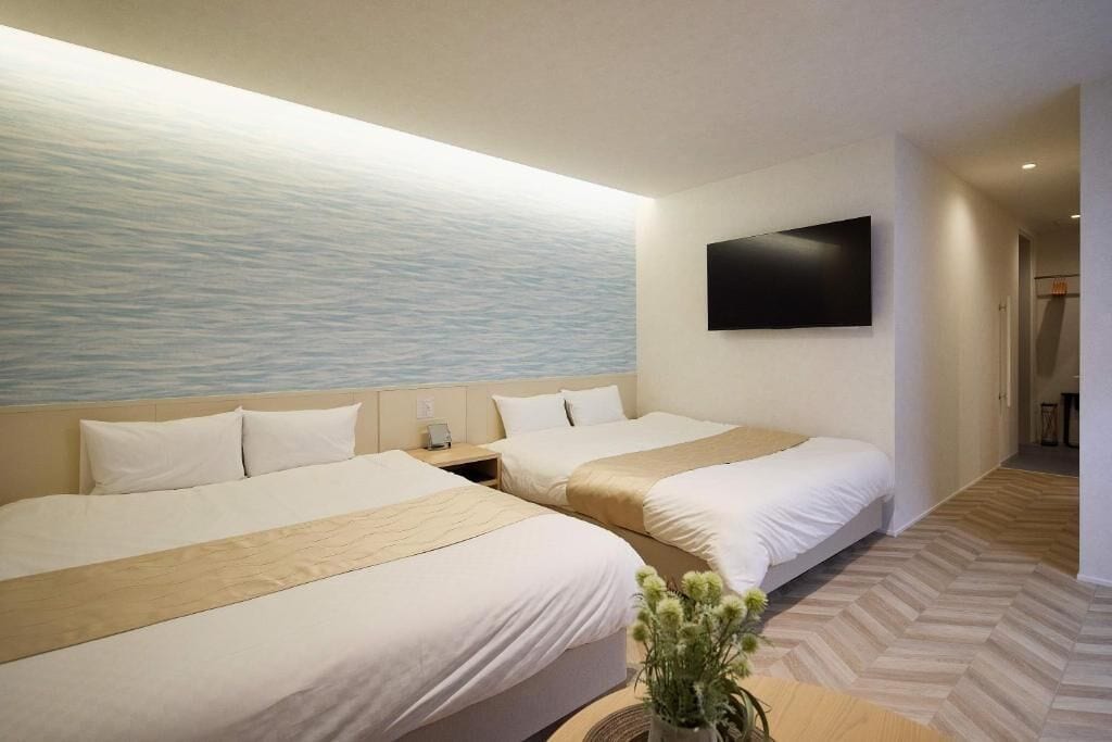 Camera d'albergo con due letti, televisione a schermo piatto e vista sul mare.