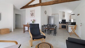 A modern living room with a dining area, kitchen, and a loft bedroom with exposed wooden beams. - Holiday Home 'Gîte L'atelier - 4 Personnes' with Private Terrace, Wi-Fi and Air Conditioning (Frossay)