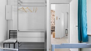A compact room with a bunk bed, a desk, and a chair. There is a door leading to a stone-walled area. - Holiday Home 'Gîte L'atelier - 4 Personnes' with Private Terrace, Wi-Fi and Air Conditioning (Frossay)