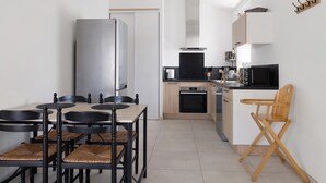 A modern kitchen with a dining area, including a table, chairs, and a microwave. - Holiday Home 'Gîte L'atelier - 4 Personnes' with Private Terrace, Wi-Fi and Air Conditioning (Frossay)