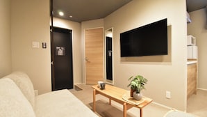 A hotel room with a bed, a small table with a plant, a TV mounted on the wall, and a microwave in the corner. - Kurashiki Station Hotel Wakana (Kurashiki-shi)