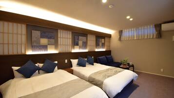 A hotel room with two beds, a small table with a plant, and a window with curtains.