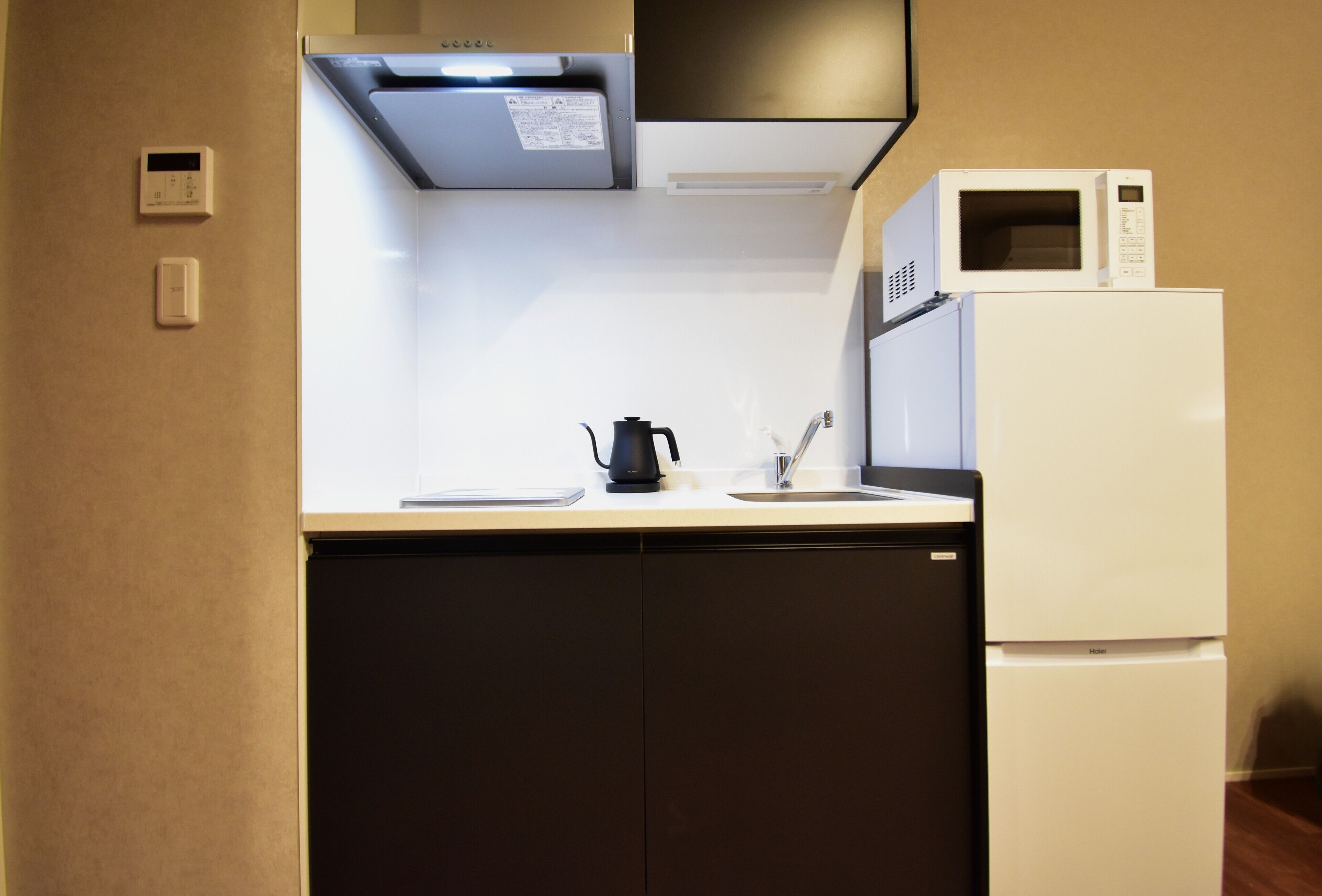 Een kleine keuken met een magnetron, waterkoker en een koelkast.