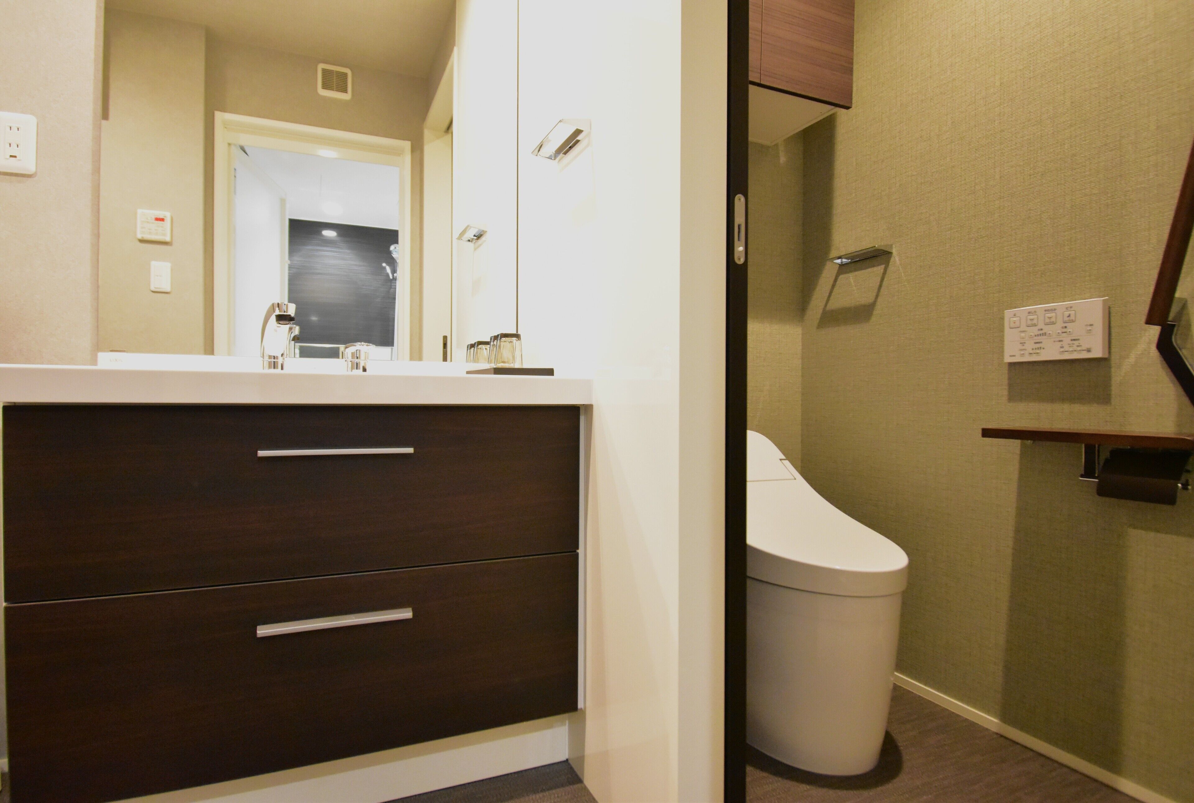A bathroom with a white sink, dark wooden cabinet, and a white toilet.
