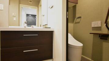 A bathroom with a white sink, dark wooden cabinet, and a white toilet.