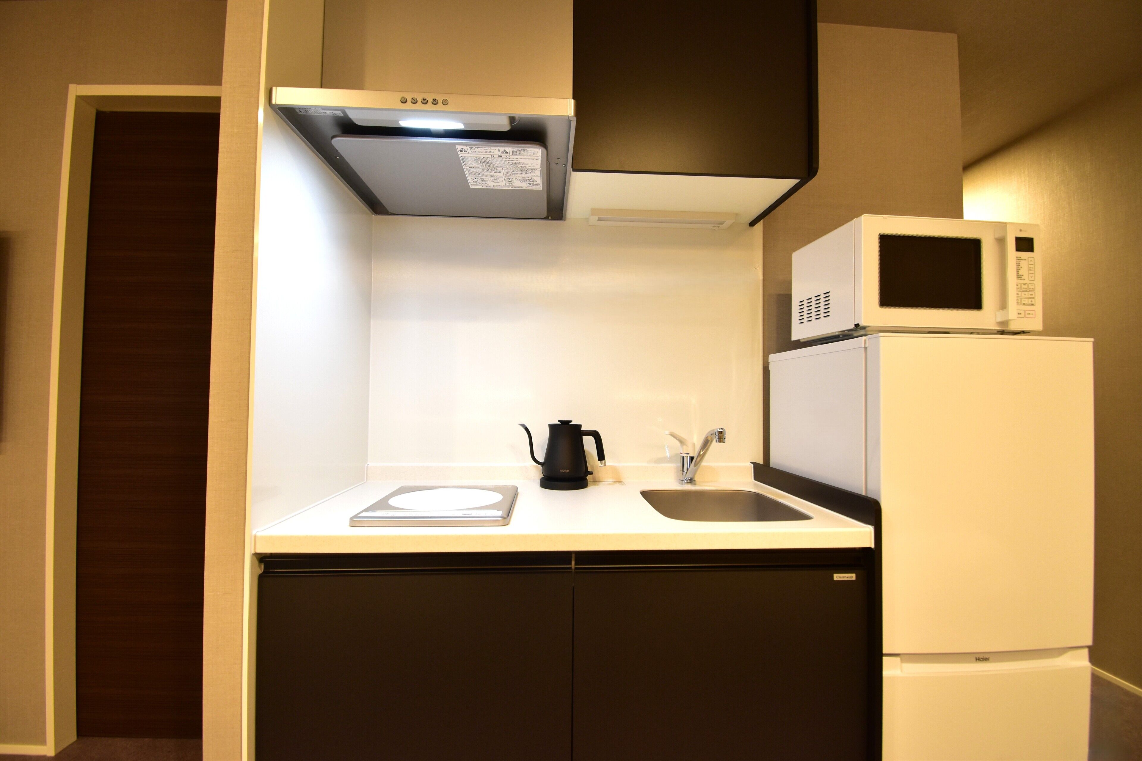 A compact kitchen with a microwave, a kettle, and a sink.