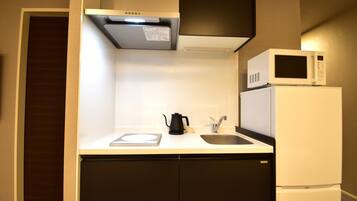 A compact kitchen with a microwave, a kettle, and a sink.
