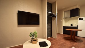 A modern kitchen with a microwave, stove, and cabinets. There's a round table with a plant and a black object on it. - Kurashiki Station Hotel Wakana (Kurashiki-shi)