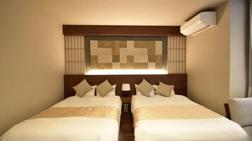 A hotel room with two beds, a wooden headboard, a wall-mounted air conditioner, and a nightstand with a lamp.