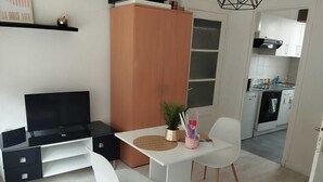 A modern kitchen with white cabinets, a black countertop, and a dining area with a white table and chairs. - Charmant Studio lumineux 30m2 Boulogne sur Mer Centre (Boulogne-sur-Mer)