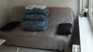 A small, cozy room with a bed, a window, and a radiator. - Charmant Studio lumineux 30m2 Boulogne sur Mer Centre (Boulogne-sur-Mer)