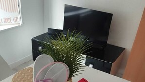 A white table with a small basket containing a toy, a book, and a red toy house. - Charmant Studio lumineux 30m2 Boulogne sur Mer Centre (Boulogne-sur-Mer)