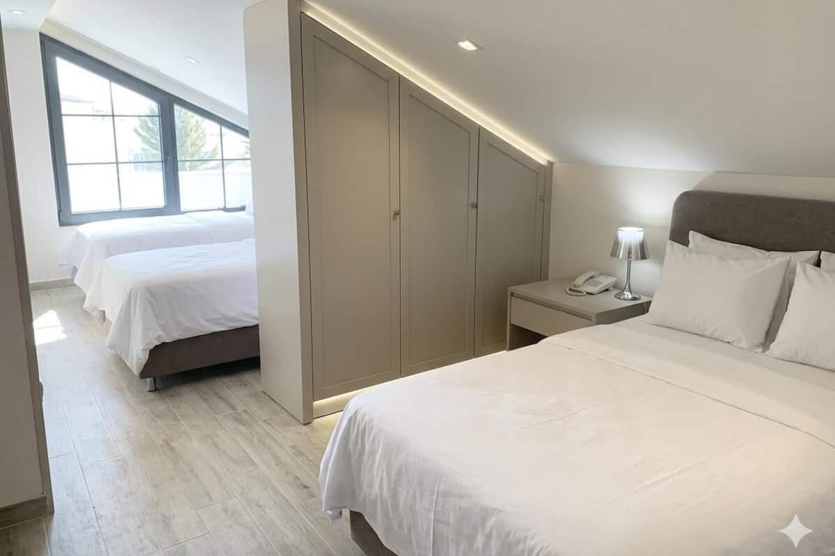 A hotel room with a large bed, a bedside table with a lamp, a wardrobe, and a window with a view.