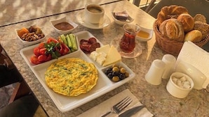 A breakfast table with a variety of food items, including eggs, cheese, olives, and bread.