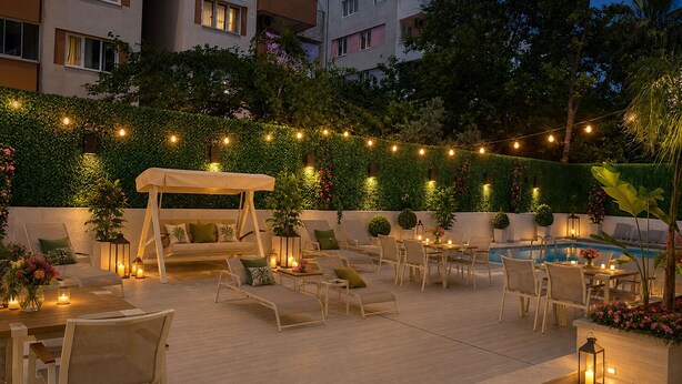 A rooftop patio with outdoor seating, a pool, and string lights.