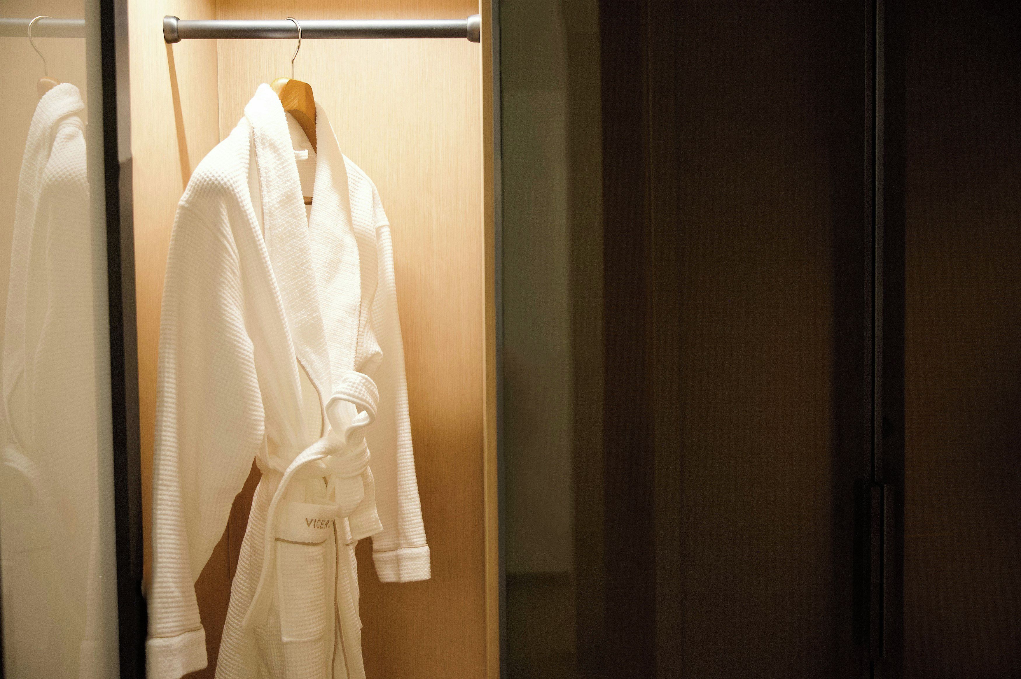 Un camí blanc penjat d'una perxa de fusta en una habitació amb una porta de vidre.