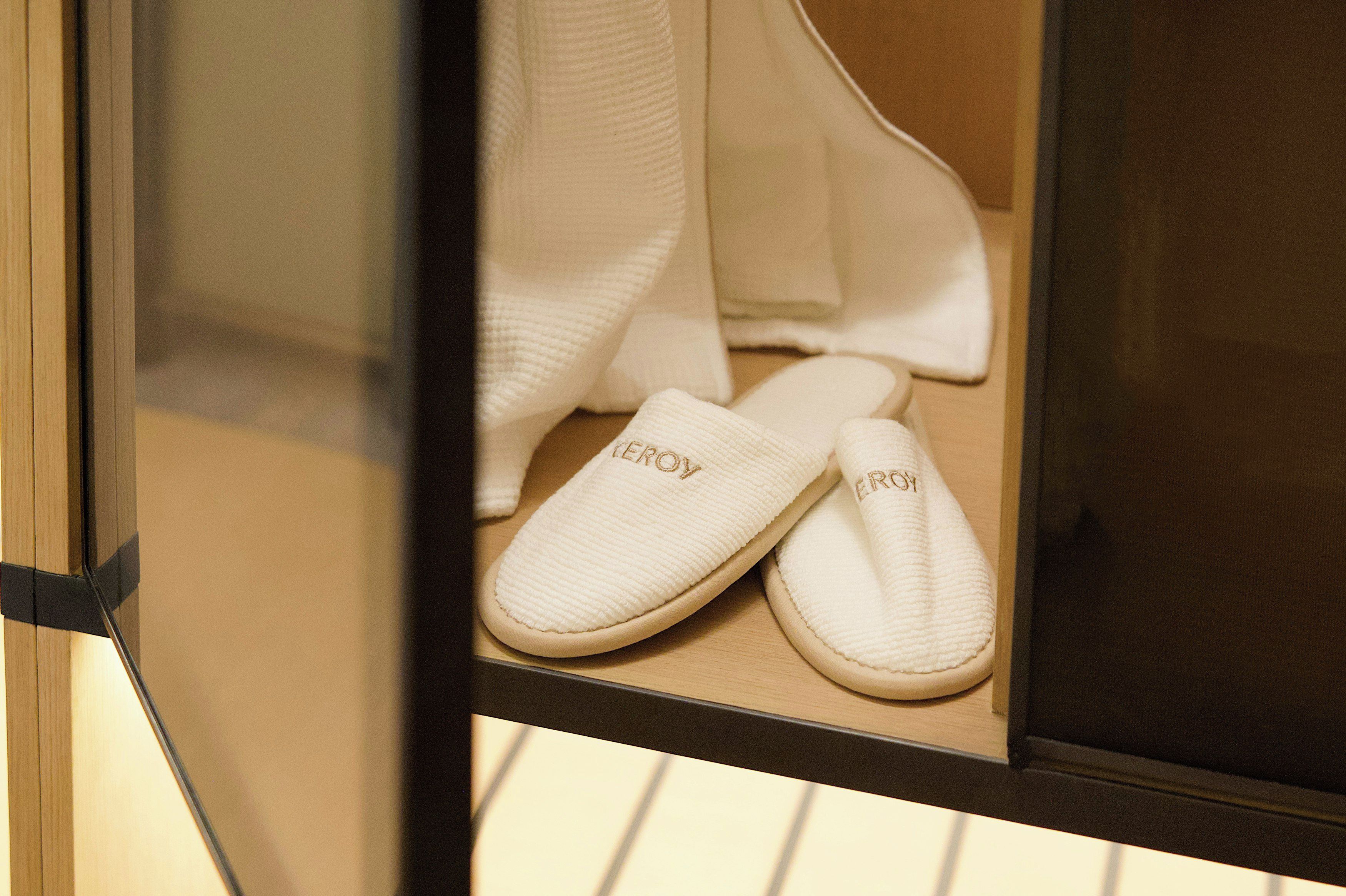 A pair of white slippers with 'ERCOY' embossed on them, placed on a wooden floor.
