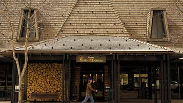A building with a wooden shingle roof, a sign reading 'Visitor Center,' and a person walking in front.