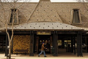 A building with a wooden shingle roof, a sign reading 'Visitor Center,' and a person walking in front. - The Observatory - A Viceroy Resort (Ketchum)