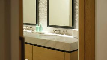 A bathroom with a double sink, two mirrors, and a white textured wall.