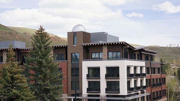 A multi-story building with a modern architectural design, featuring balconies and a prominent dome structure on the roof. - The Observatory - A Viceroy Resort (Ketchum)