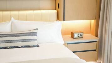 A neatly made bed with a pillow and a blanket, a bedside table with a radio, and a wooden headboard.