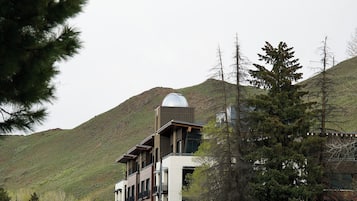 A modern building with a unique dome structure, surrounded by trees and hills.