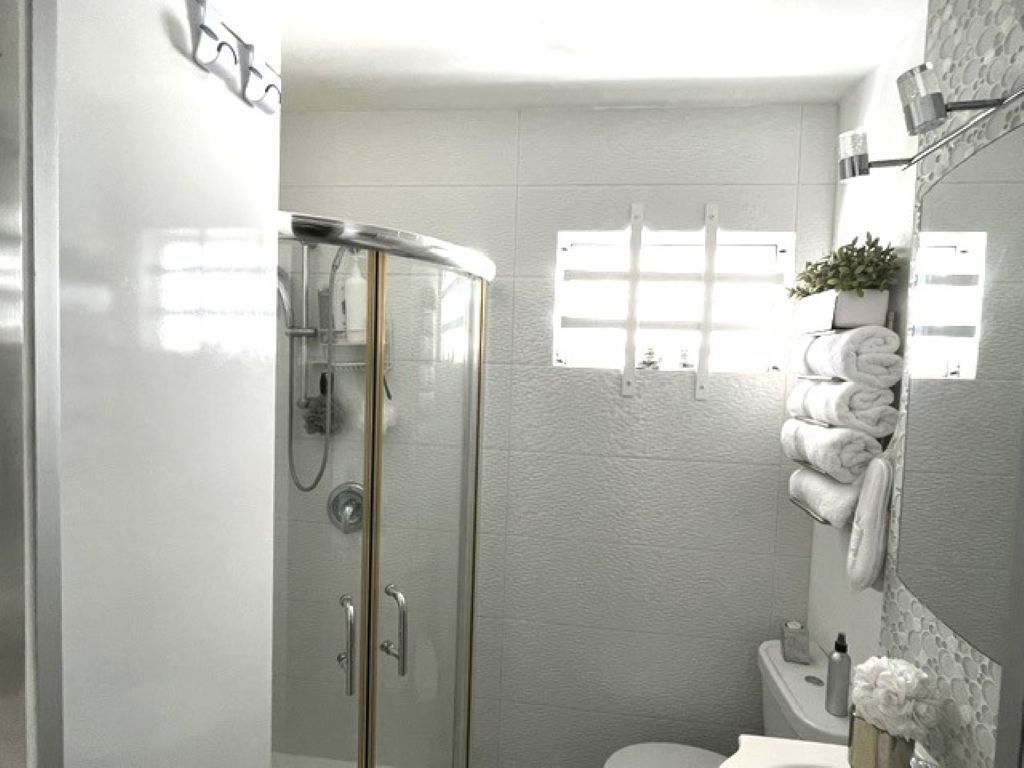 Une salle de bain moderne avec une douche à parois de verre, des toilettes et un lavabo surmonté d’un miroir.
