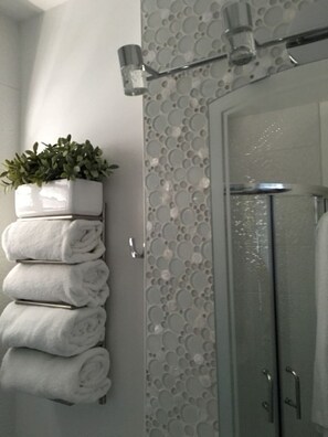 A bathroom with a glass shower door, a towel rack with folded towels, and a potted plant. - Winter in sunny Barbados @ Rockley Golf & Country Club. (Bridgetown)